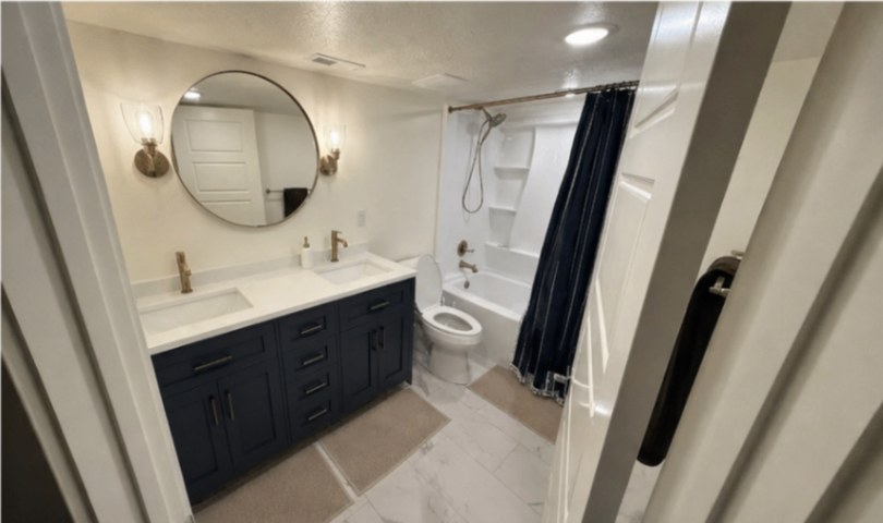 Basement full bathroom with navy vanity and marble-look tile