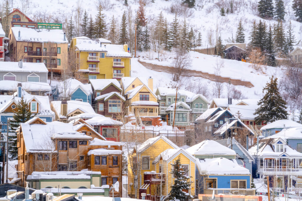 Snow-covered Colorado ski towns bustling with winter activities and scenic mountain views under a clear blue sky.